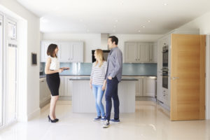 Realtor Showing Young Couple Around Property For Sale, standing in a kitchen part of the home page slide show